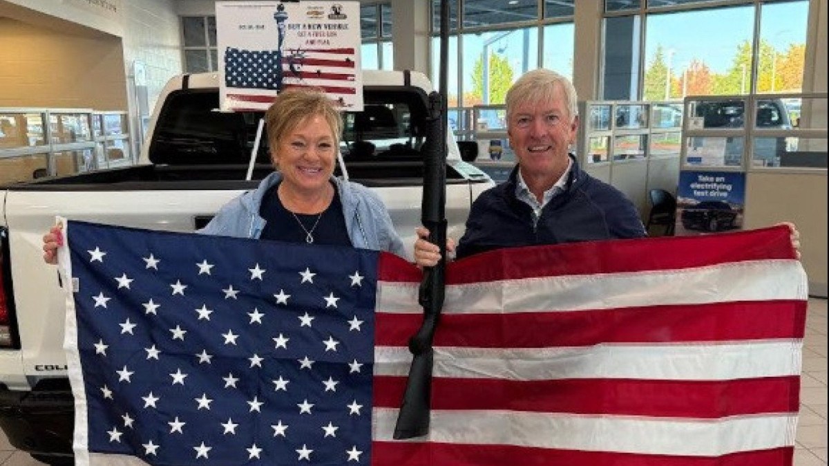 Moradores de Idaho, nos EUA, posam com bandeira dos EUA e espingarda após compra de carro 0 km da Chevrolet 