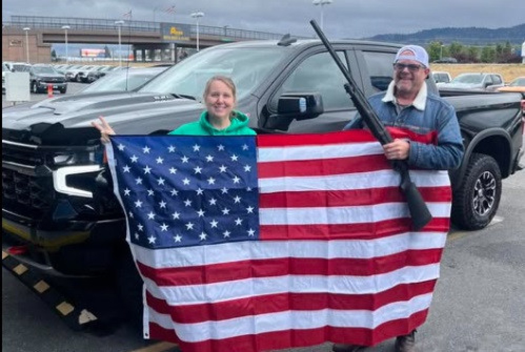 Moradores de Idaho, nos EUA, posam com bandeira dos EUA e espingarda após compra de carro 0 km da Chevrolet 