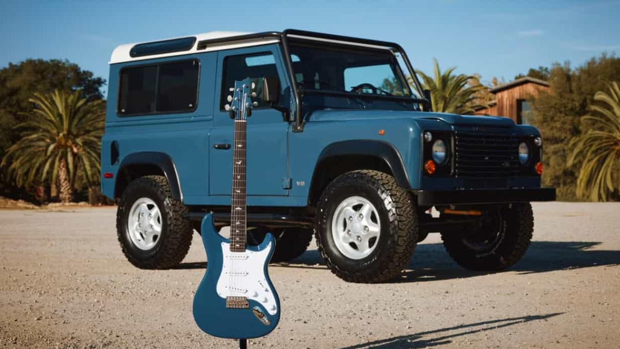 A guitarra azul da edi&ccedil;&atilde;o limitada ao lado do Land Rover Defender cl&aacute;ssico, refletindo a parceria com John Mayer inspirada nas cores do SUV -  (crédito: Divulga&ccedil;&atilde;o/Land Rover)